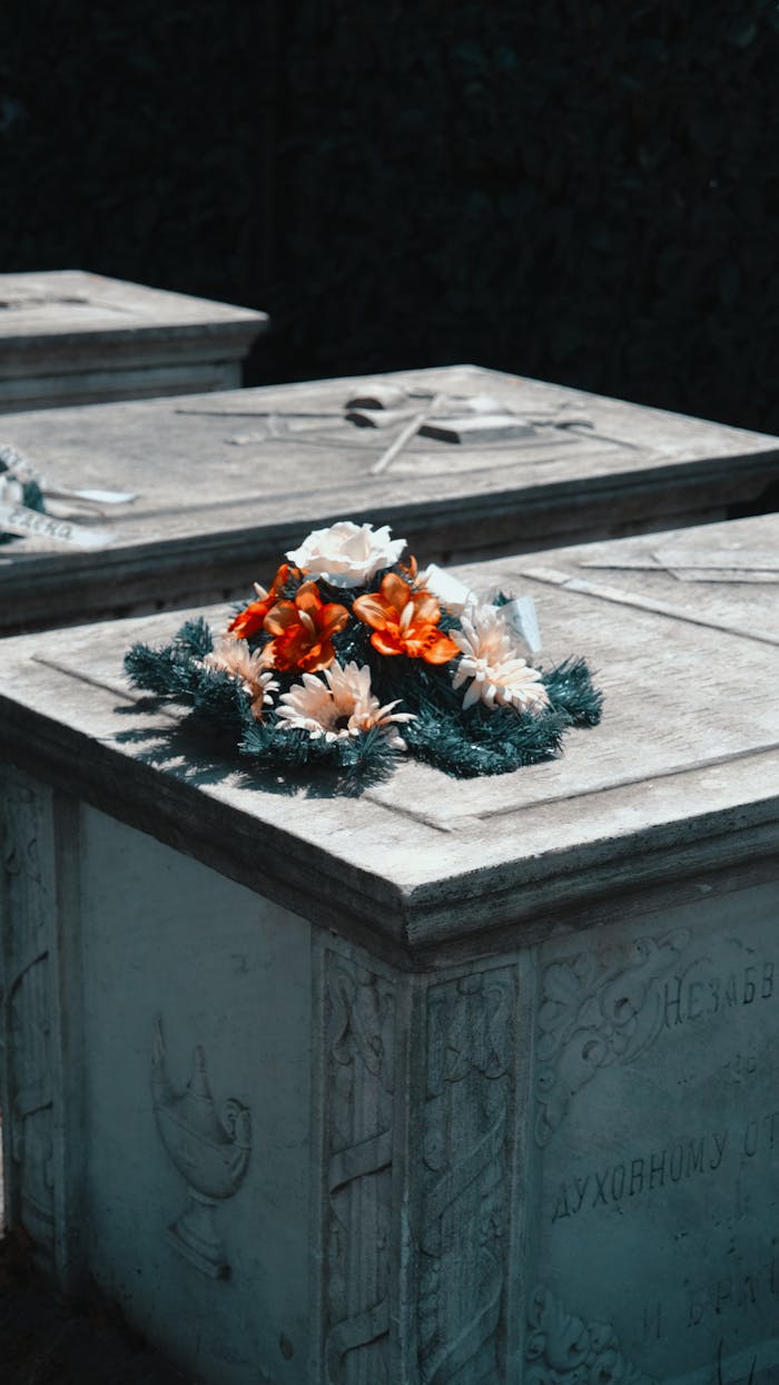 A serene image of flowers placed on a tombstone in a quiet cemetery, evoking solemn reflection.